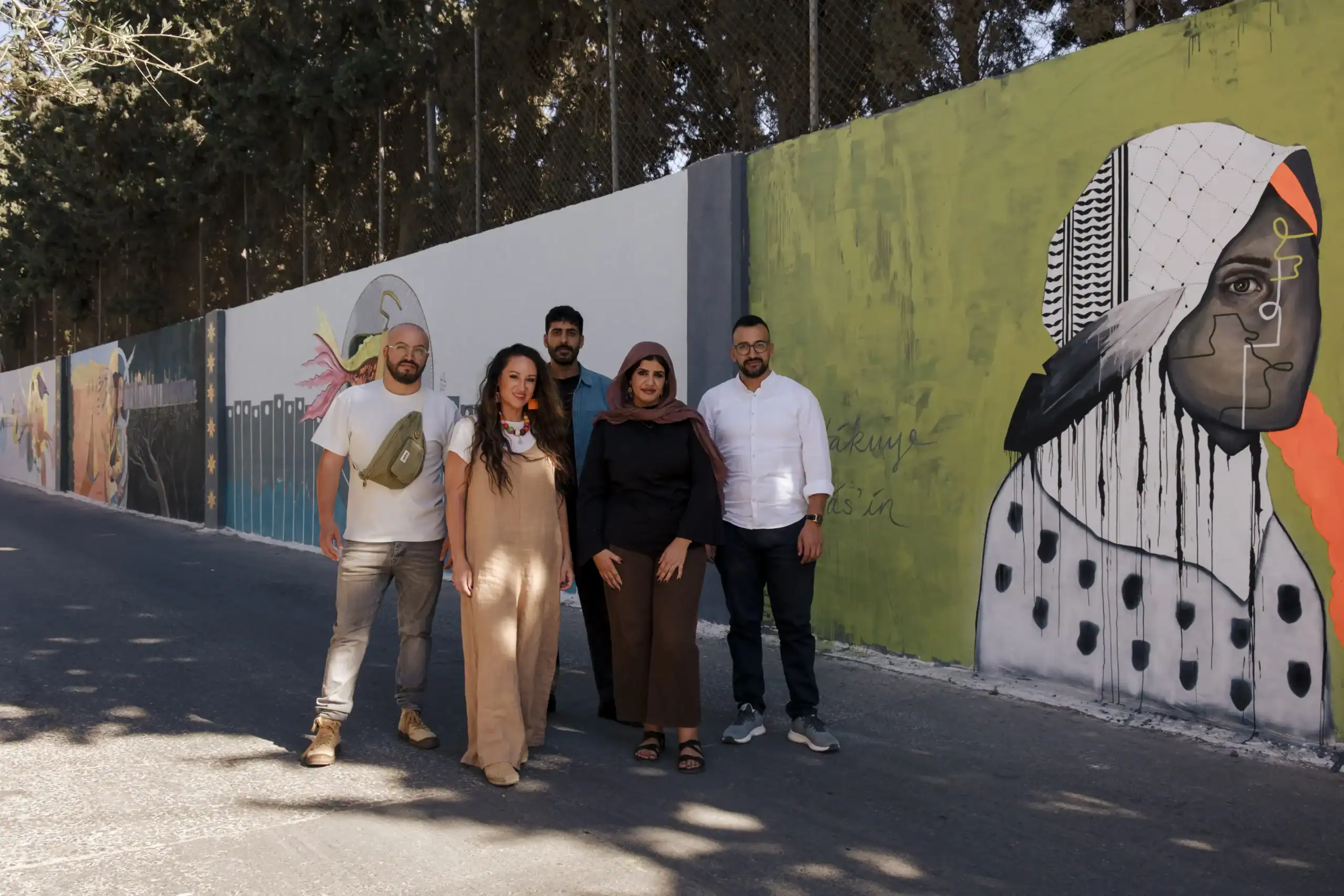 The Walls of Resilience artists in front of the completed murals at Aida Camp